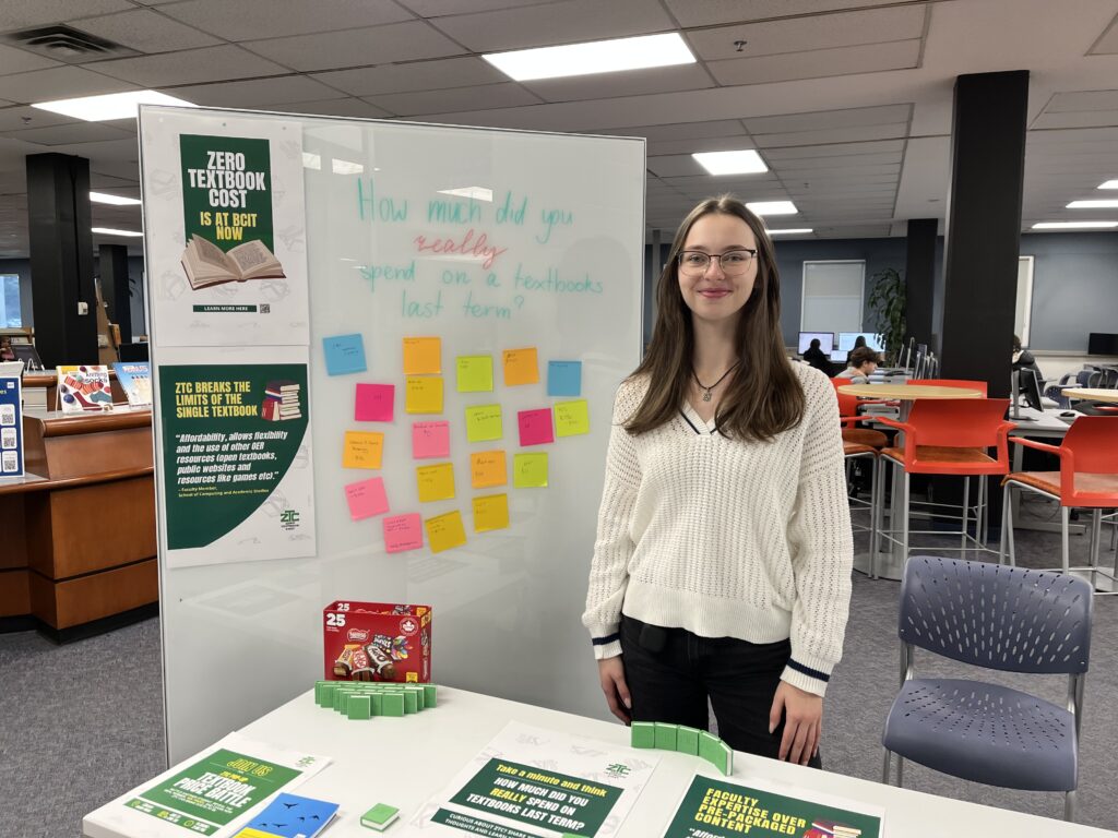 A ZTC pop-up table and a whiteboard and a ZTC team member Mariia featuring posters, colourful sticky notes, and 3D-printed books at a ZTC Pop-Up event.