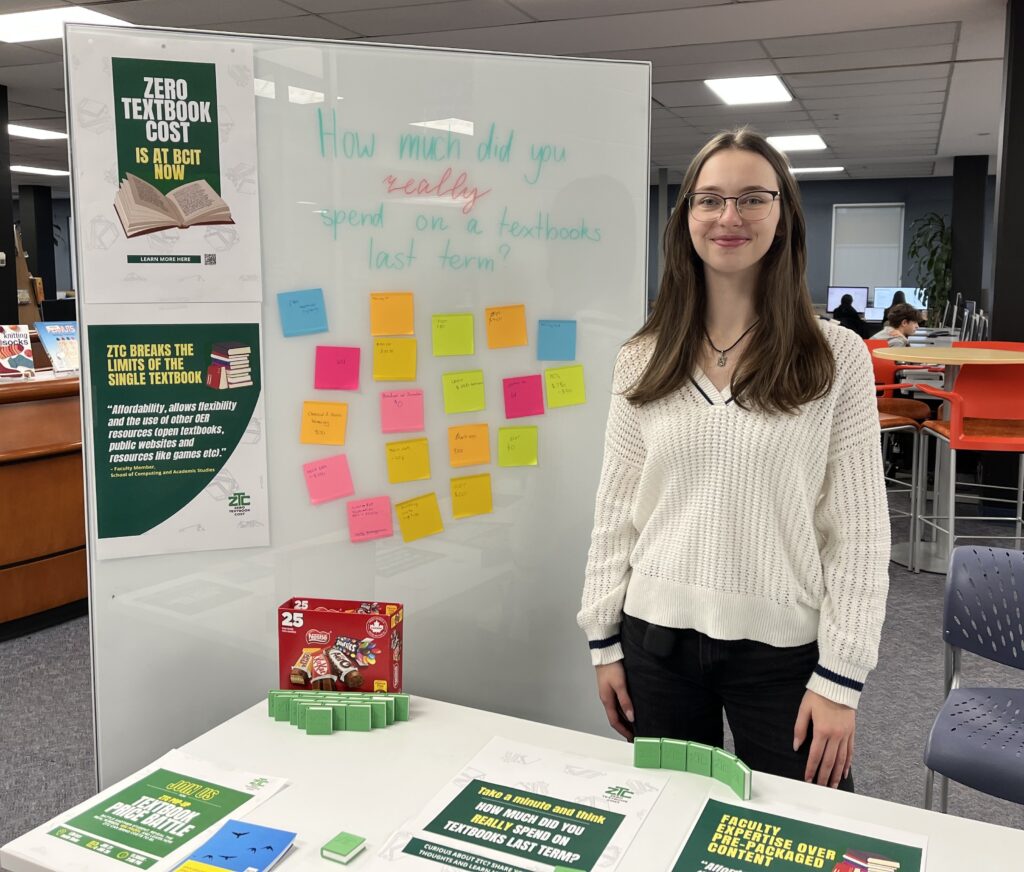 A ZTC pop-up table and a whiteboard and a ZTC team member Mariia featuring posters, colourful sticky notes, and 3D-printed books on a ZTC Pop-Up event.